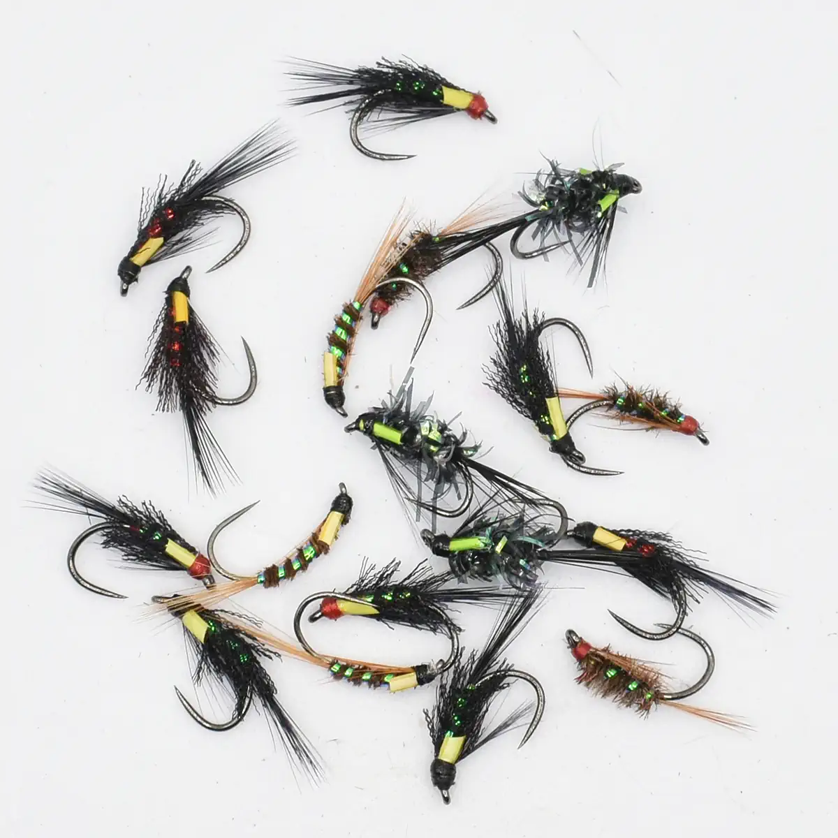 Collection of colorful fishing flies with beads and feather tails laid on a white background, used for fly fishing