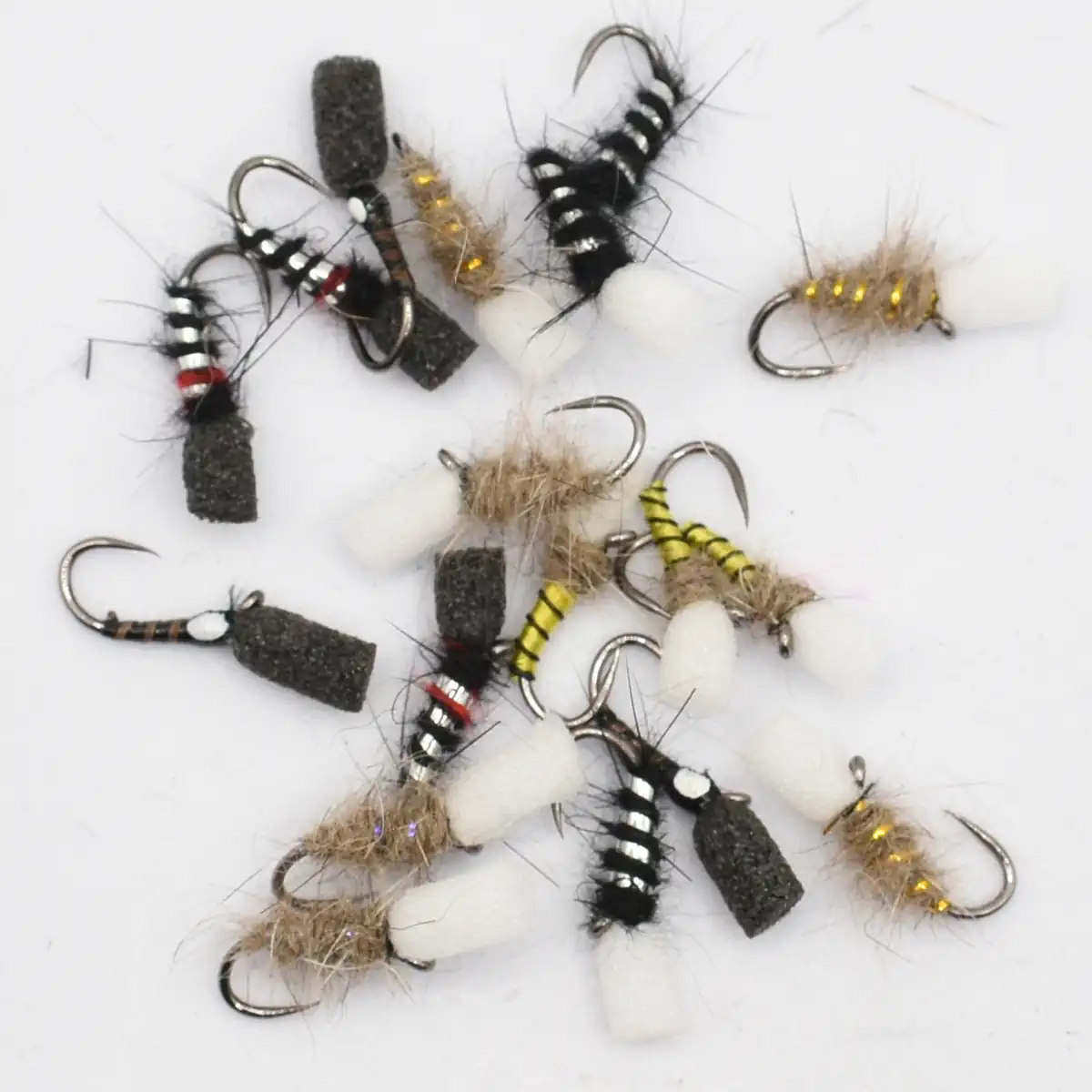 Assorted fly fishing flies with black, white, and yellow fuzzy bodies and hooked metal hooks on a white background.