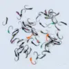 Assorted small fishing jigs with colorful bodies scattered on a pale surface.