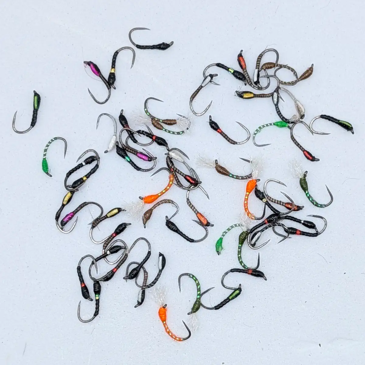 Assorted small fishing jigs with colorful bodies scattered on a pale surface.