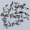 Assorted bead-head fishing flies with colorful bodies scattered on a light surface.