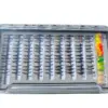 Open tackle box showing neatly arranged rows of fishing flies, with bright feathered lures along the right edge.