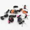 Assorted black fly fishing lures with orange and pink accents on a white background.