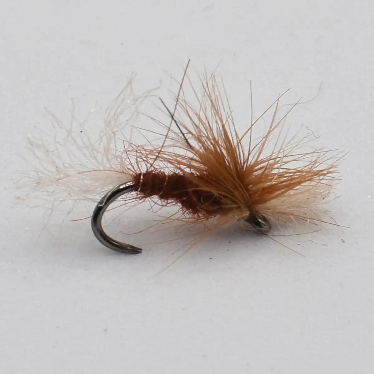 Brown dry-fly fishing lure with fluffy brown hackle tied to a curved hook.