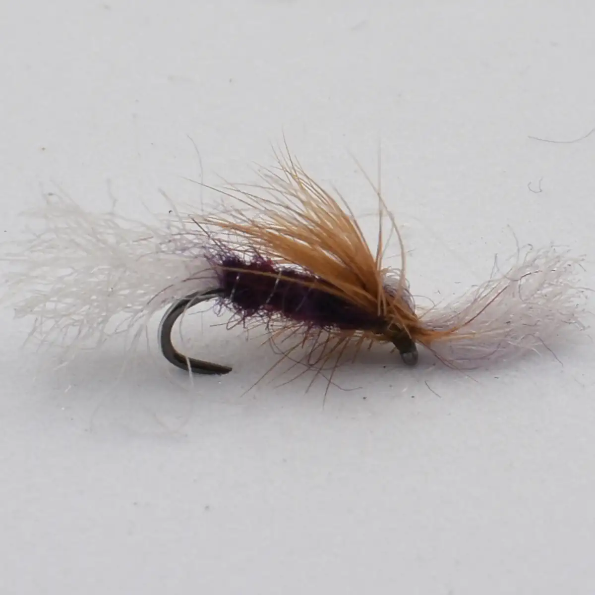 Close-up of a brown and tan fishing fly with fluffy hackle on a curved hook (fly fishing lure)