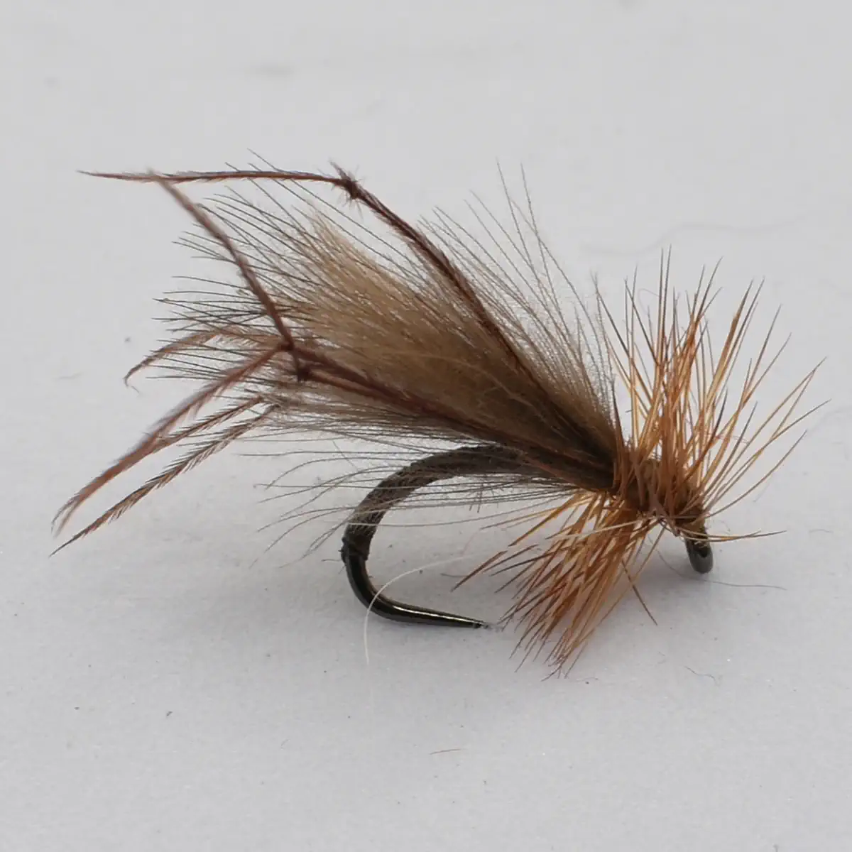 A brown, hairy fishing fly tied on a curved hook, used as a lure for fly fishing
