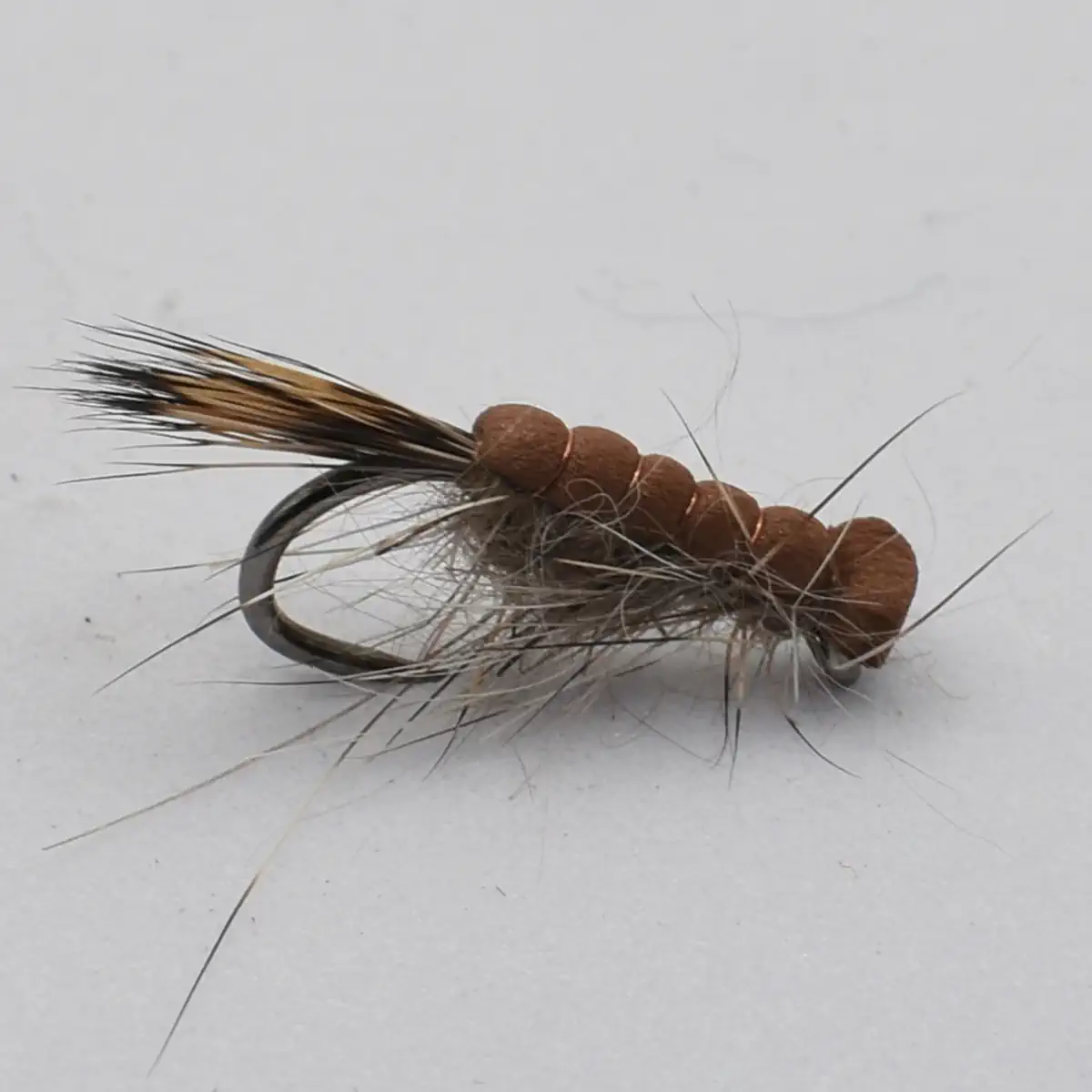 Close-up of a bead-headed fly fishing lure with an orange segmented body and brown hackle feathers.