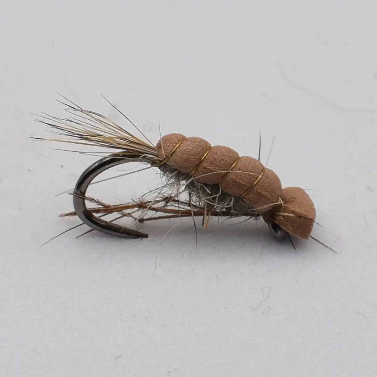 Tan segmented fishing fly nymph tied on a curved hook with natural fibers and thread wraps.