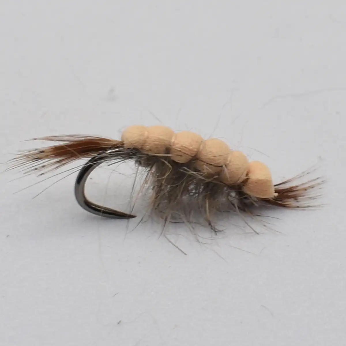 Beige bead-headed fishing fly with brown feather tail and grey body for angling a trout-imitating lure