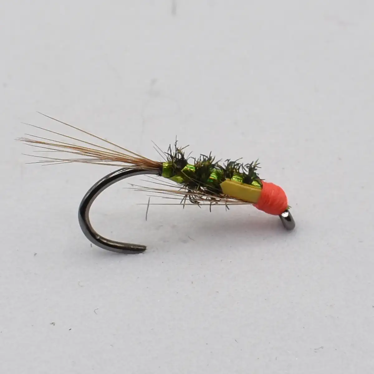 Close-up of a fishing fly lure with an olive-green body, orange head, and wispy tail on a curved hook.