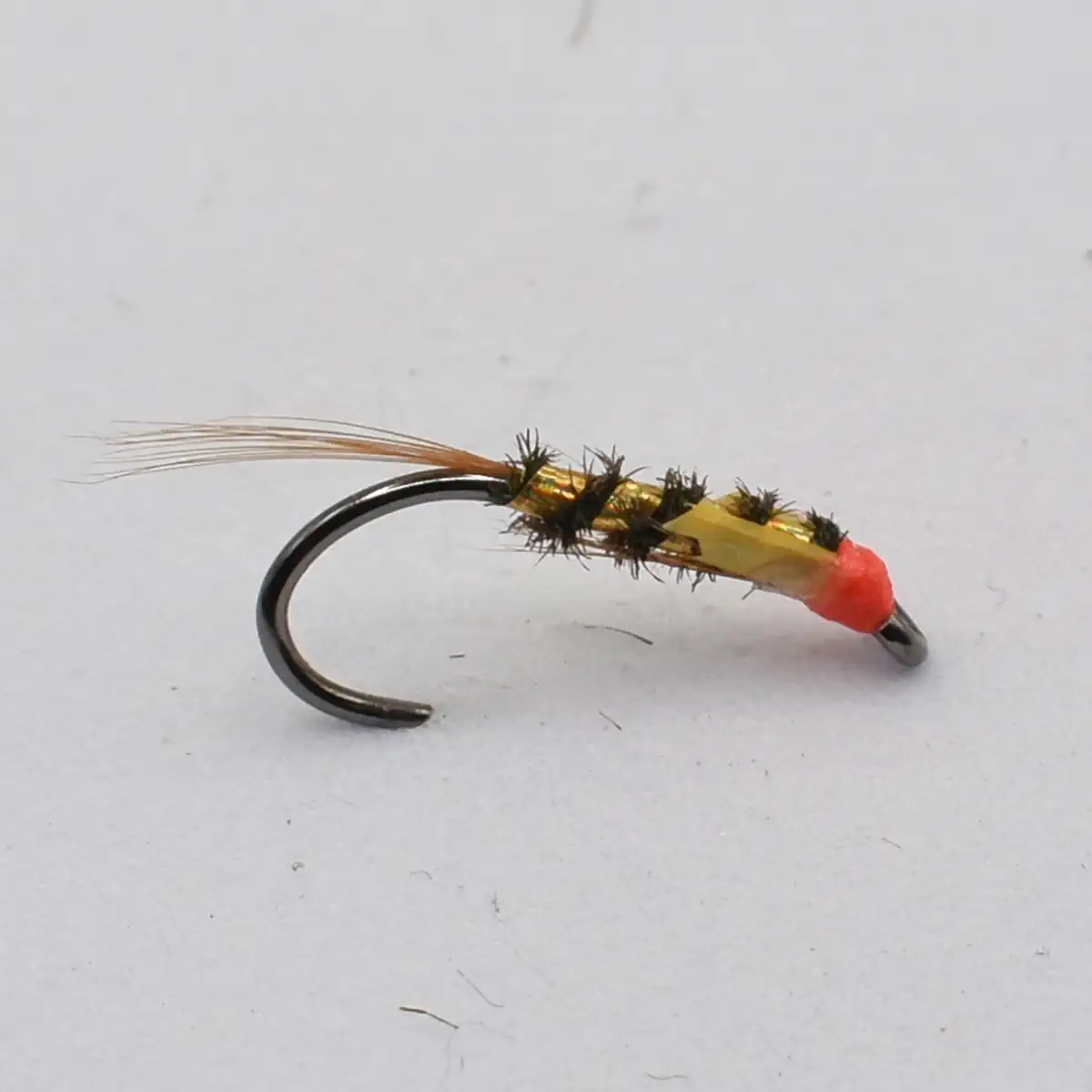 Artificial fishing fly tied on a curved hook with a gold body, black spiky legs, red bead, and orange tail for trout catching.