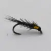 Black fishing fly with wispy black hackle and yellow tag tied to a curved hook.