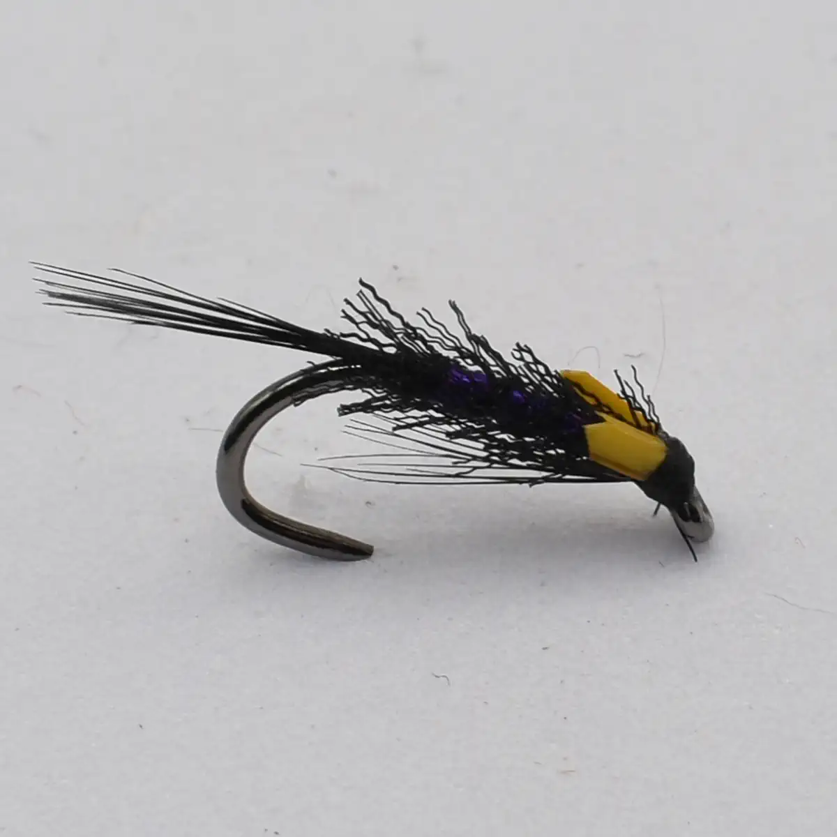 A metallic fishing hook tied with black feathers and a yellow band, used as a streamer fly for fly fishing