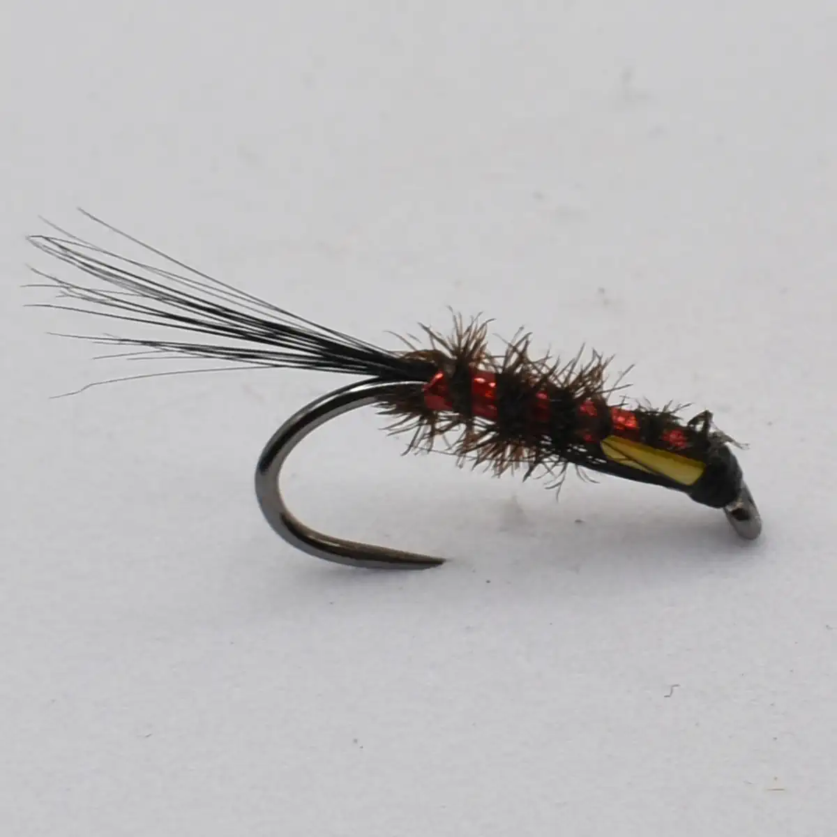 Bead-headed fishing fly with red and black body and long black tail feathers on a curved hook (fly fishing lure).