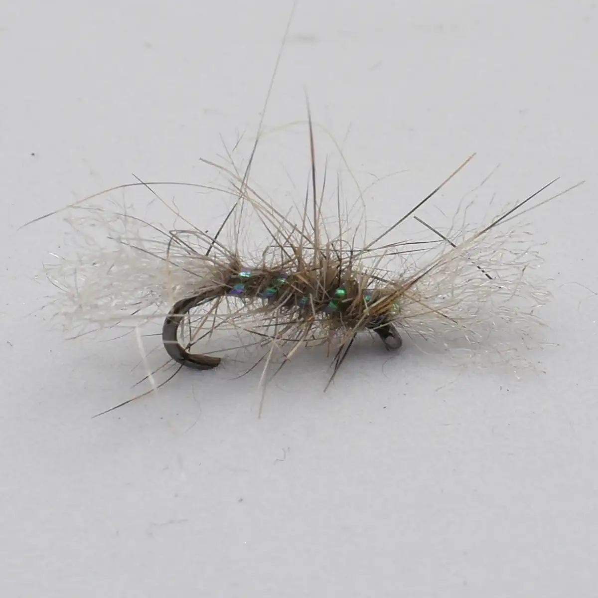 Close-up of a bead-headed fishing fly with iridescent beads and wispy tan hackle on a curved hook.
