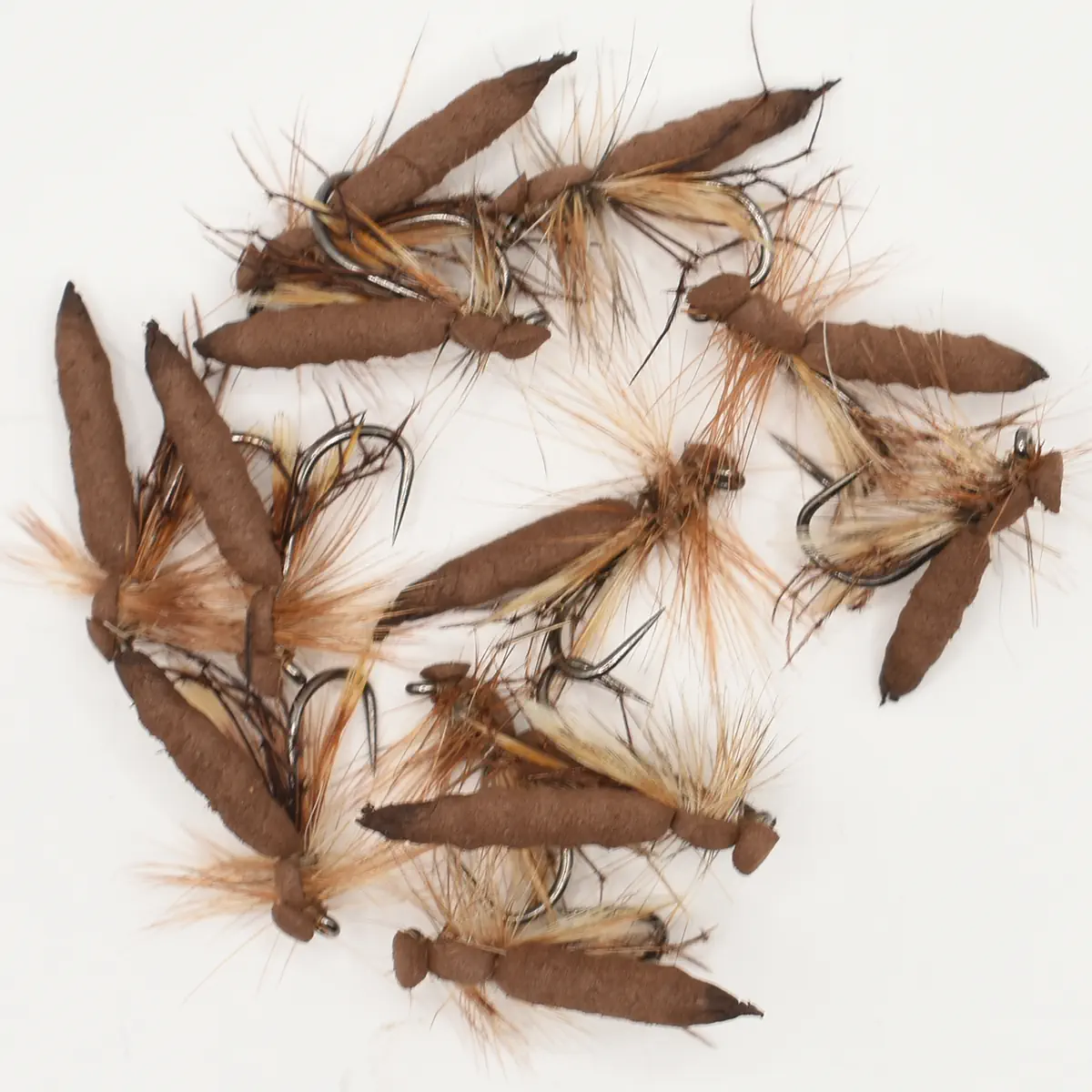 Assorted brown fishing flies with feather hackles laid out on a white surface on a looped line hook.