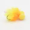 Bright yellow fuzzy pom-pom-like brush with orange-tinted bristles on a white surface.