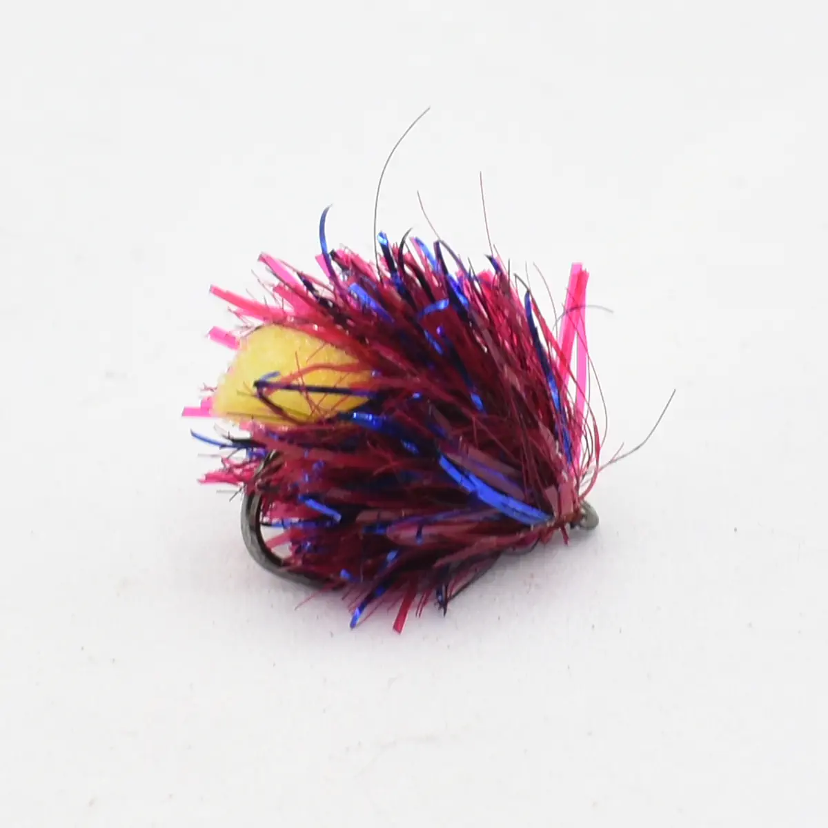 Colorful fishing lure with pink, red, and blue tinsel strands and a small hook visible.