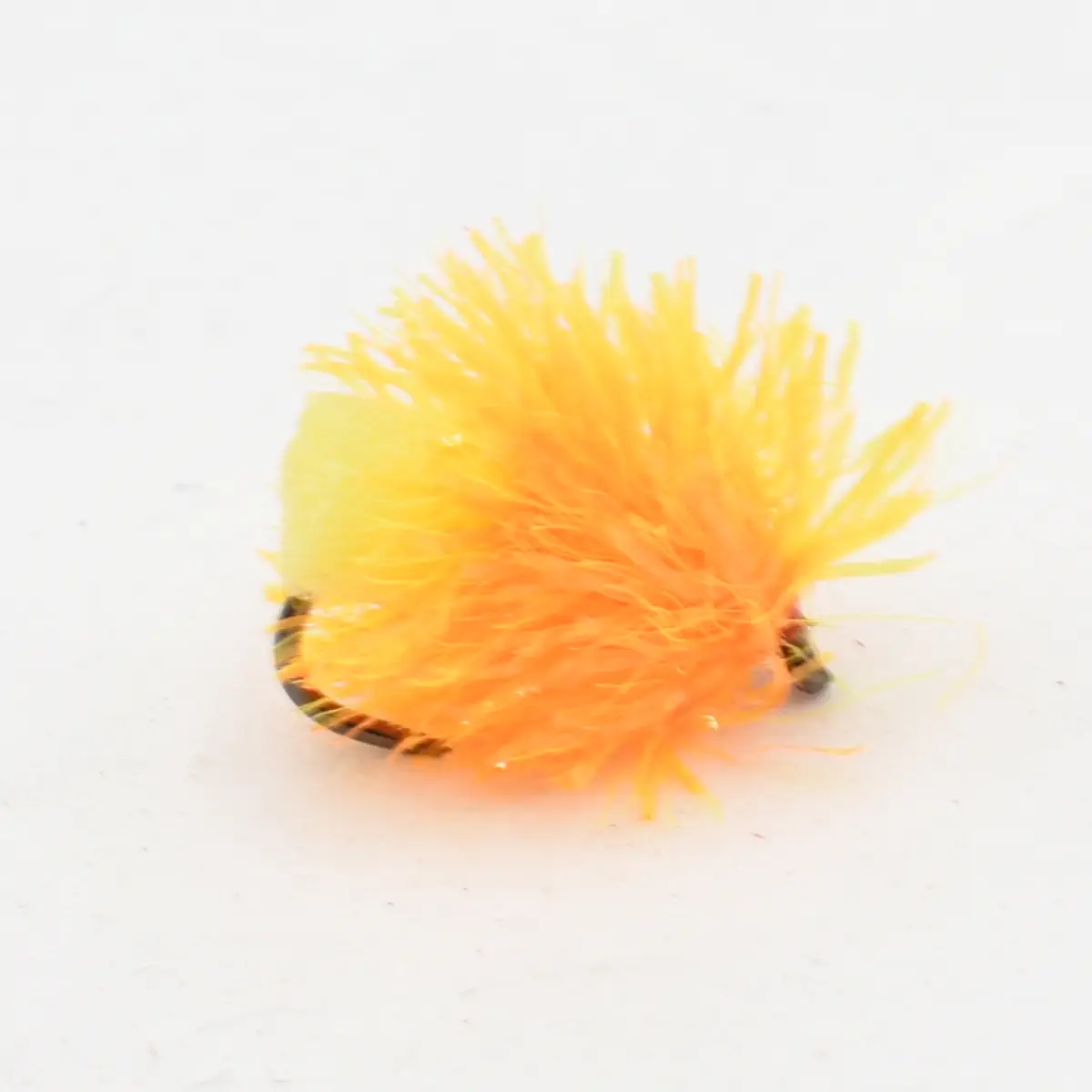 Bright orange fuzzy fishing lure (fly) with a dark hook partly visible, used to attract fish in fishing.
