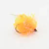 Close-up of an orange fuzzy pom-pom fishing lure with shiny strands and a small hook nearby.