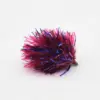 Red and blue tinsel fishing jig with metallic strands and a small hook end on a light background