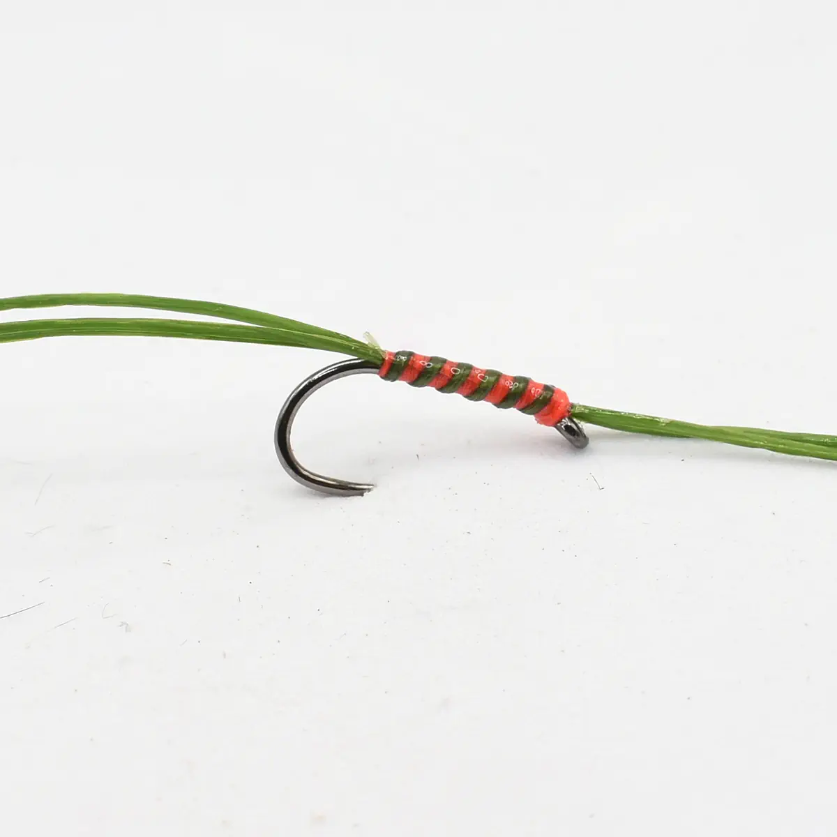 Close-up of a fishing hook wrapped with red and green thread tied to a green line