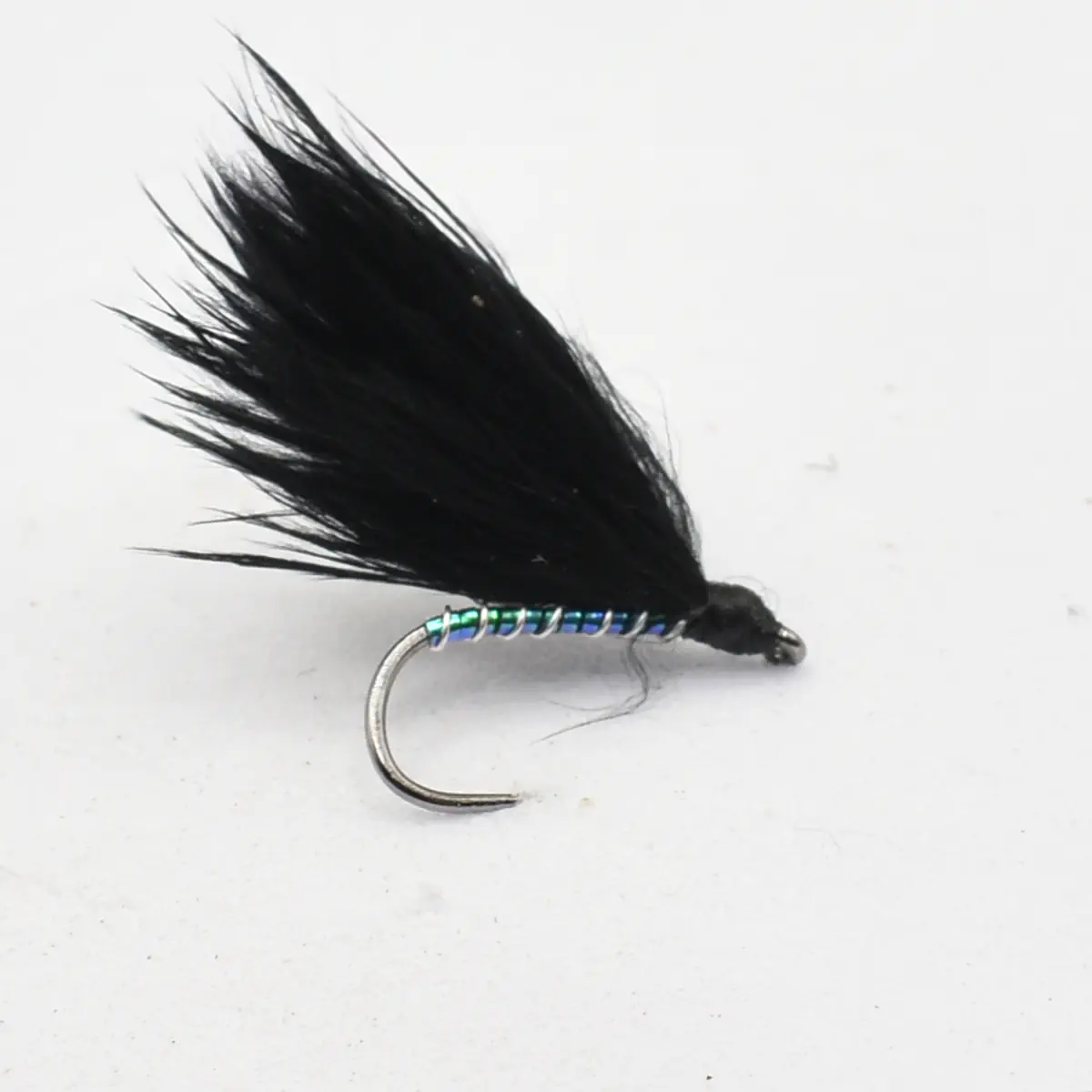 Black feathered fishing fly tied on a curved hook with a shiny blue-green ribbed body, used for fly fishing.
