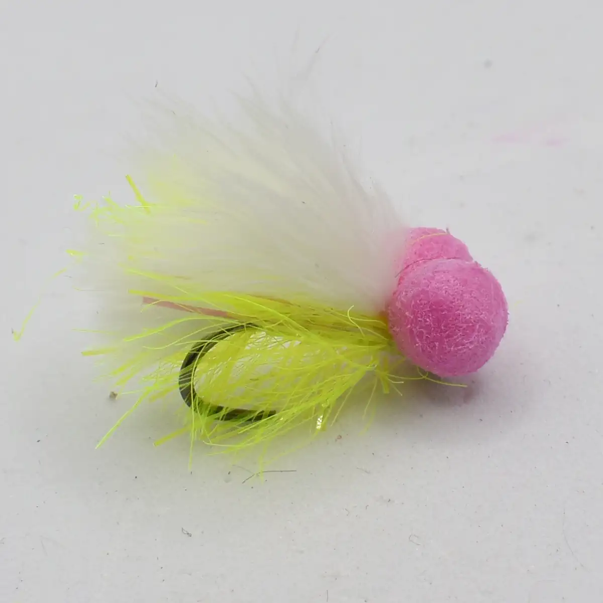 Pink foam-headed fishing lure with bright yellow feather tail and a visible hook, used for fly fishing or trolling.