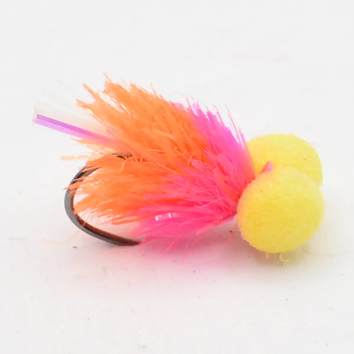 Bright fishing lure with pink and orange feathers and yellow foam bead on a hook, against a white background.