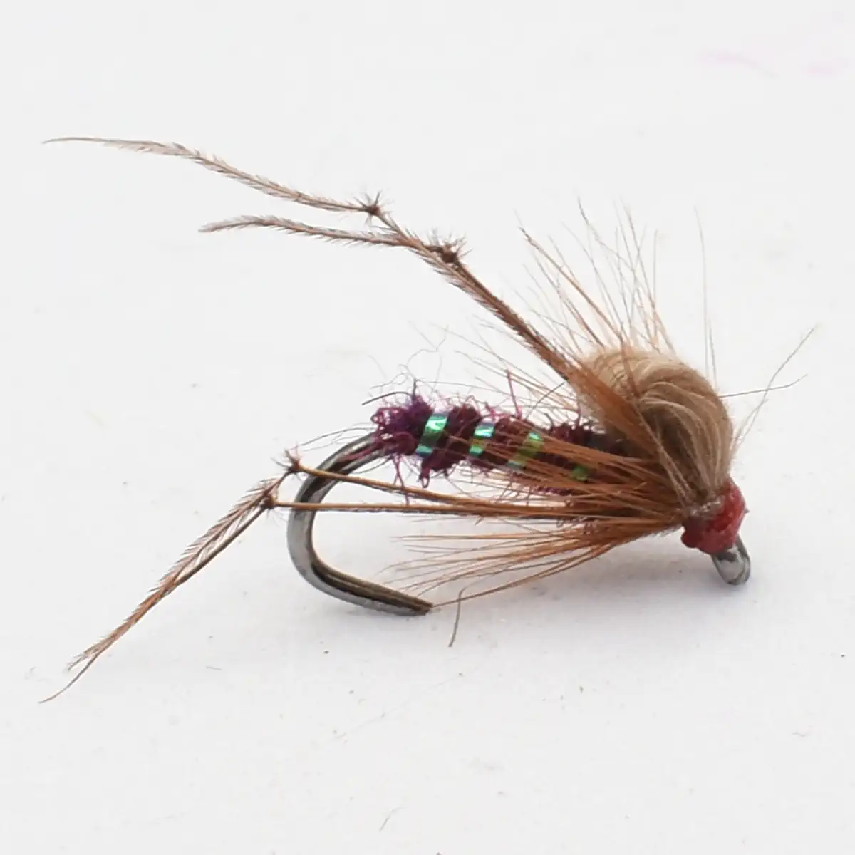 A detailed fishing fly with brown fibers, iridescent green wrap, and a red head tied to a curved hook on a white background