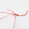 Close-up of a red beaded fishing lure tied to a hook with red thread strands extending outward.