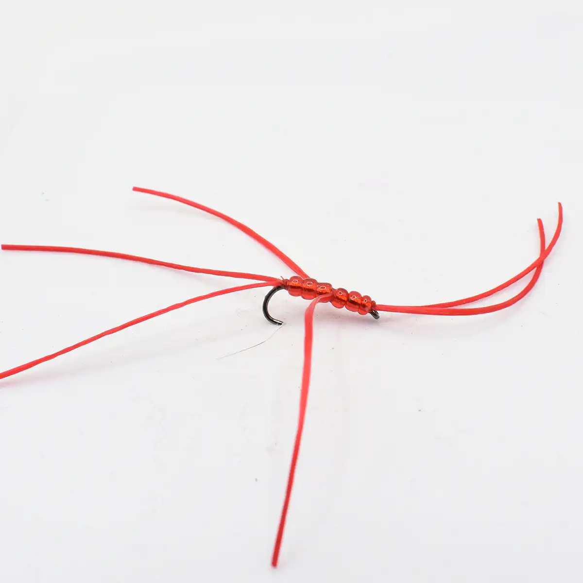 Close-up of a red beaded fishing lure tied to a hook with red thread strands extending outward.