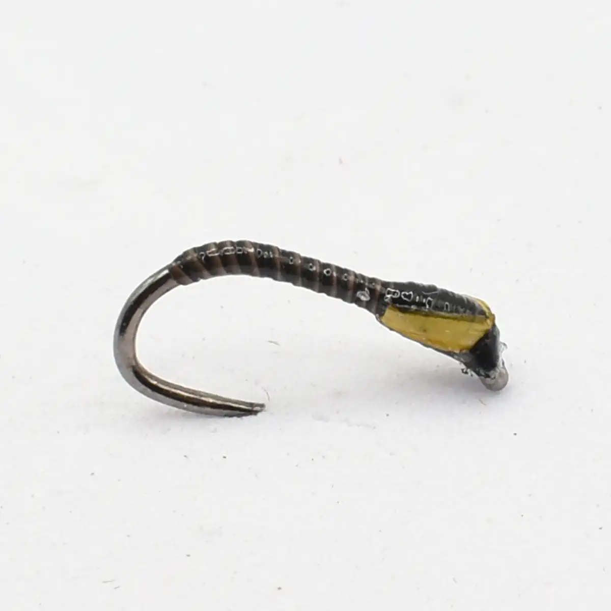 Small fishing hook with a black thread-wrapped body and yellow accents, tied for a lure