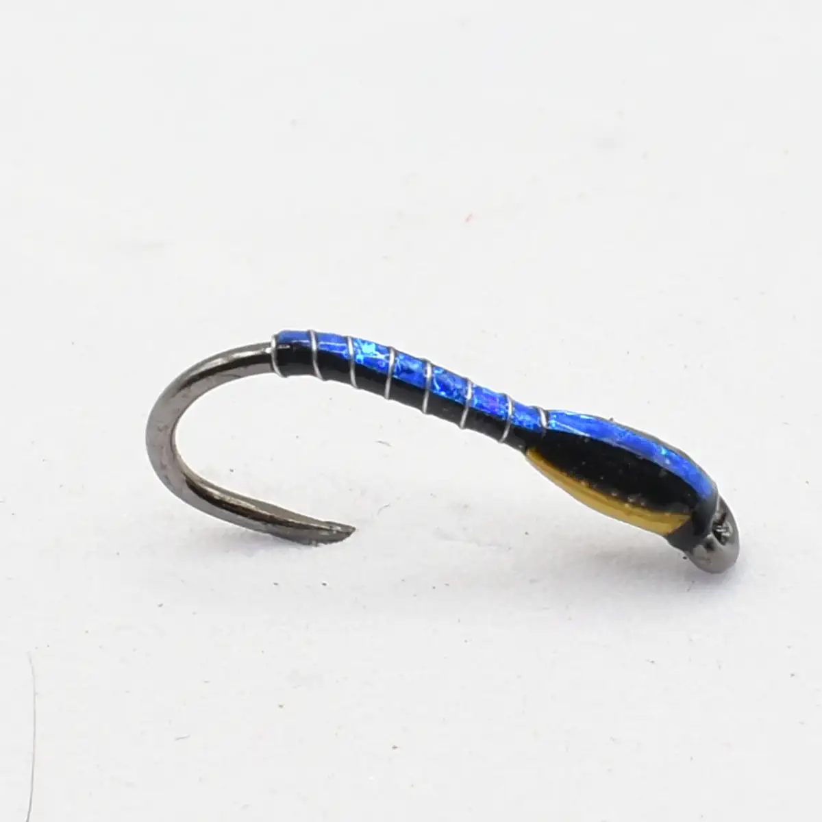 Small blue and gold metal fishing lure with a curved hook, laid on a white background.