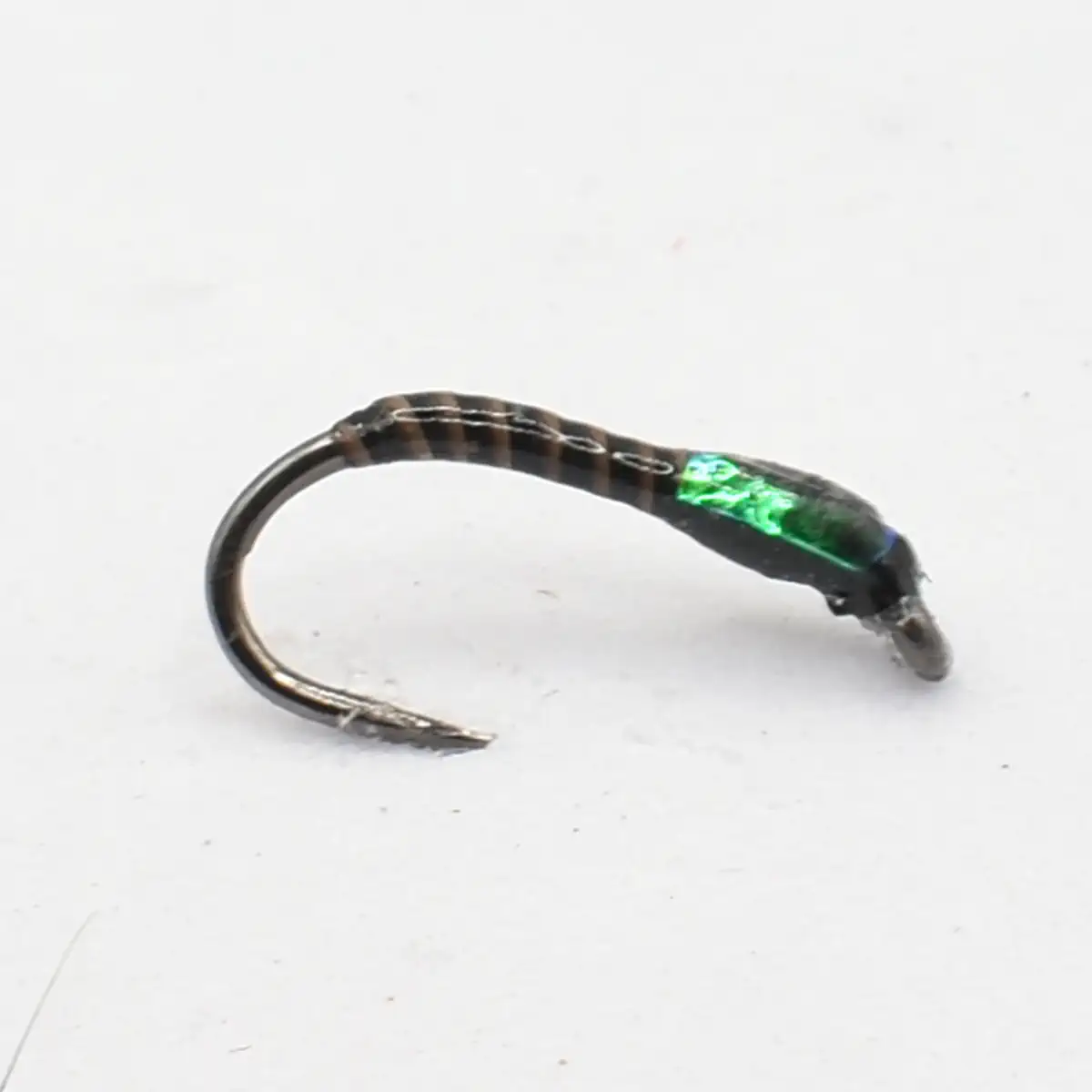 Small curved metal fishing hook with a shiny green wrapped lure on a white background