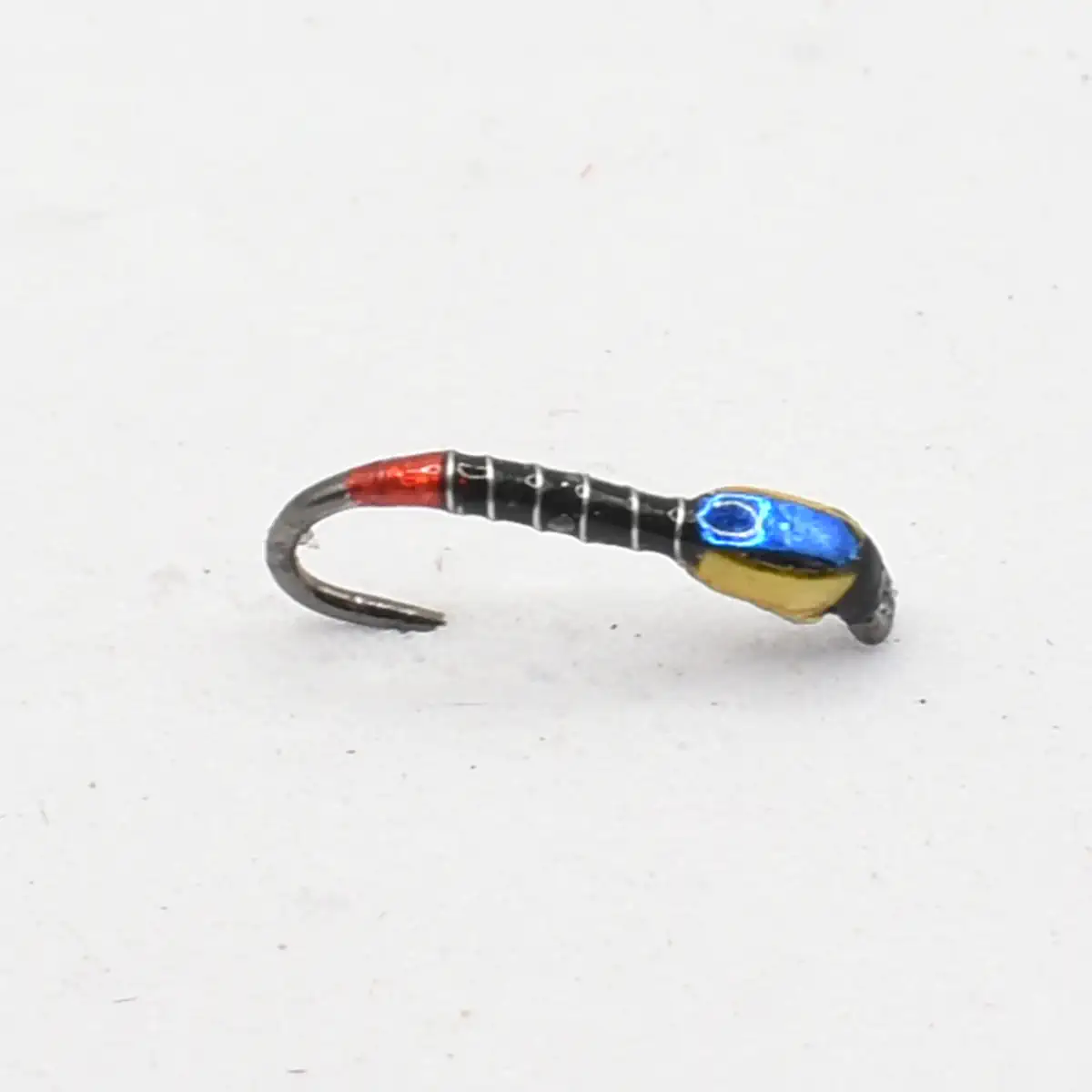 Small colored fishing jig with a red tip and blue bead on a curved hook is shown as a lure.