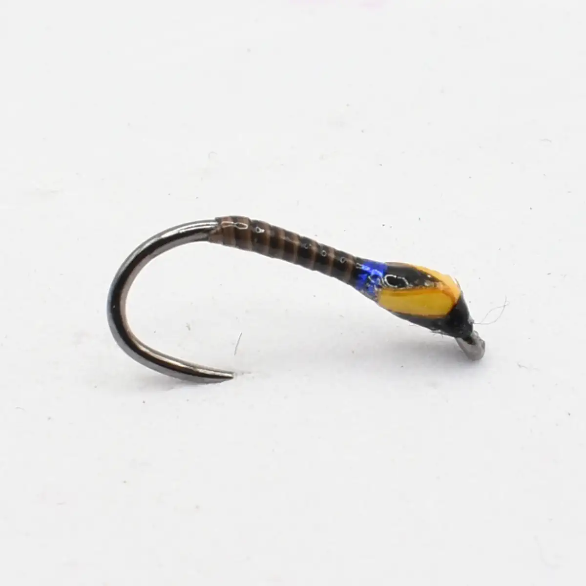 Close-up of a metal fishing hook with a wrapped brown body and a yellow bead near the eye.