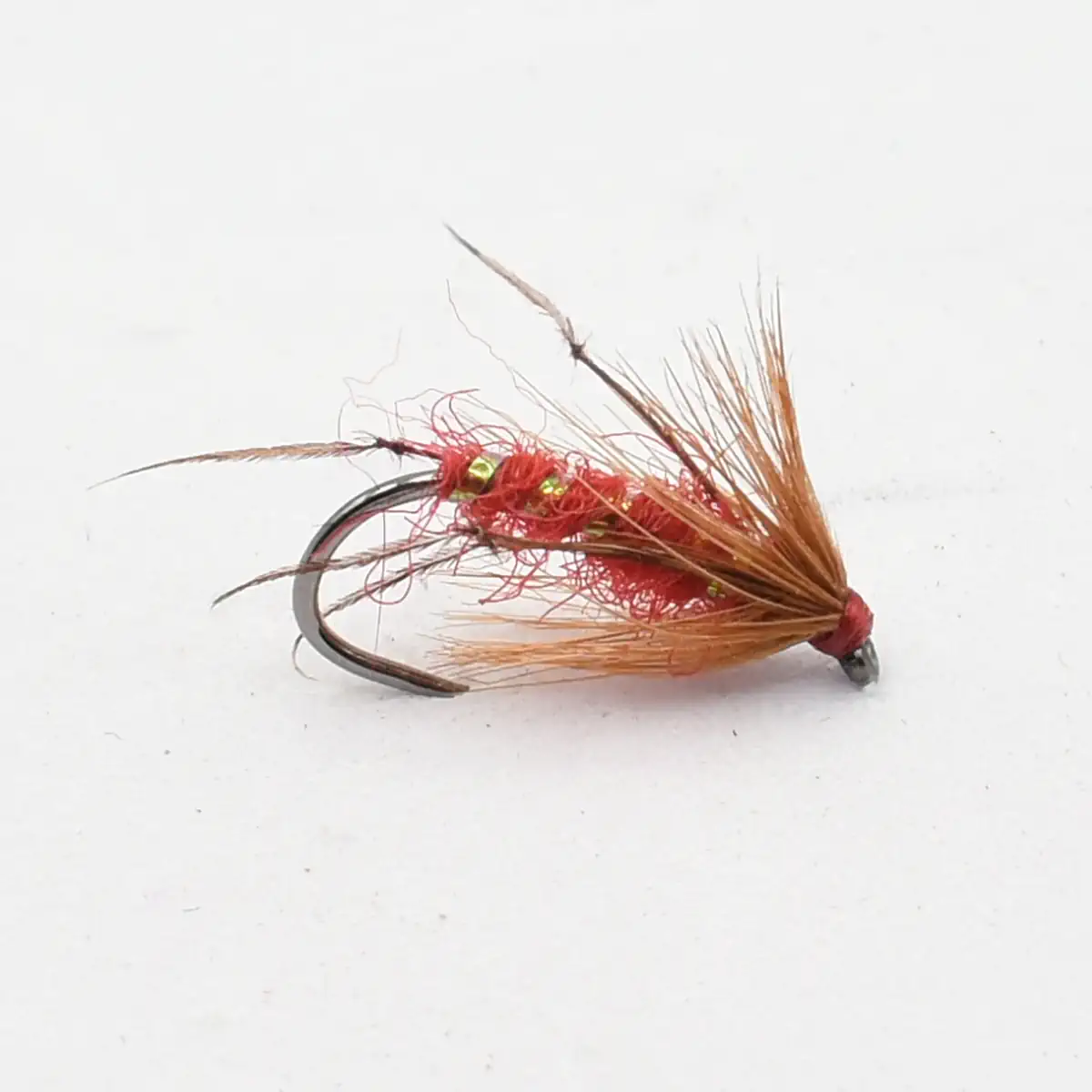 Red feathered fly fishing lure tied on a curved hook, used for trout fishing maneuvers.