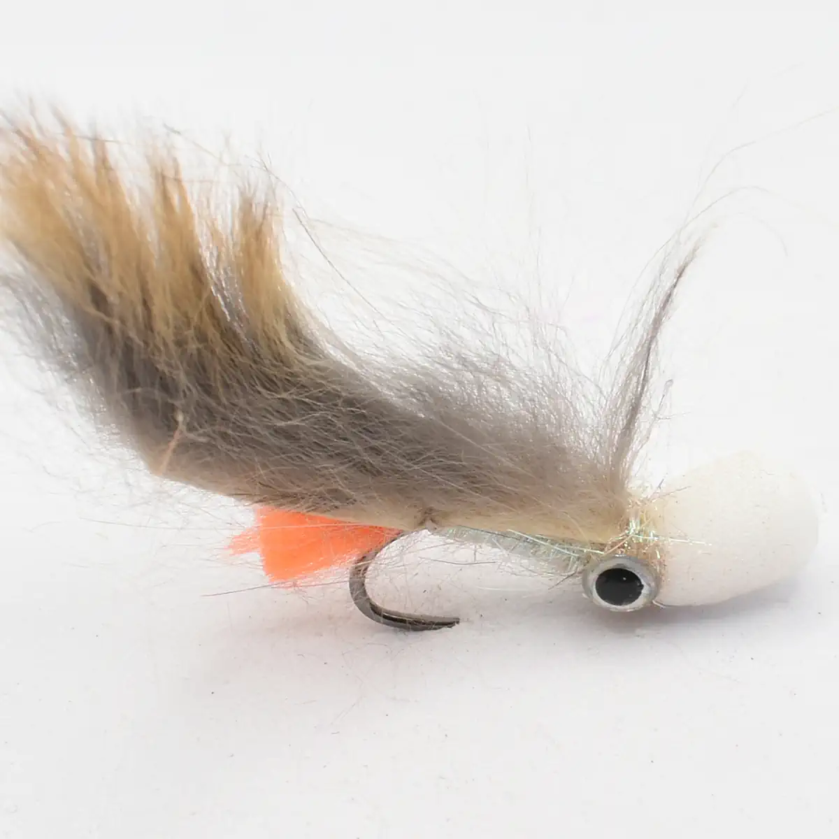 Fishing fly lure with white body, brown fur tail, orange accent, and a visible hook mid-body of the fly