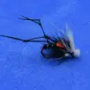 Black fishing fly lure with orange head and white-tipped tail laid on a blue background; used for fly fishing