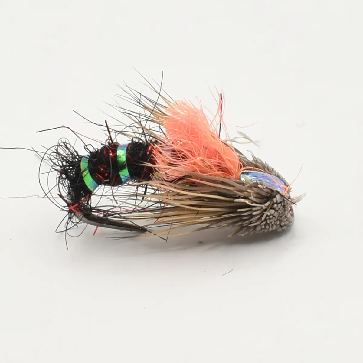Colorful fly fishing lure lying on its side: black body with green metallic bands, pink fuzzy hackle, and brown feathered tail.