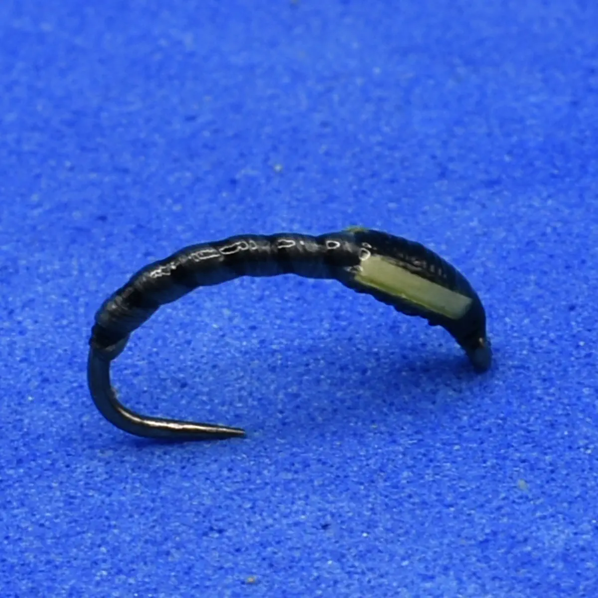 Curved black wire with a small beige rectangular block attached, shown on a blue background.