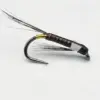 Close-up of a brown segmented fishing fly with a curved hook and wispy black tail fibers, featuring gold ribbing.