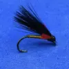 Eyed fishing fly with black feather tail and red body tied to a curved hook on blue background