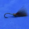 Close-up of a black fishing fly with a glossy green body and dark feather tail on a blue background.