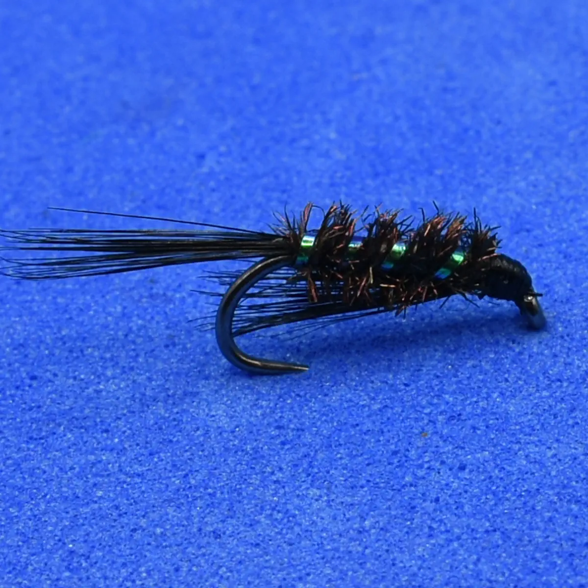 Bead-headed black woolly bugger fly with marabou tail and green beads on a blue background