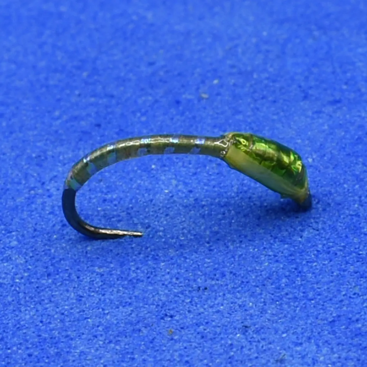 Translucent green fishing lure with a curved body and a single hook on a blue background.