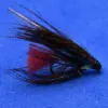 Close-up of a fishing fly with a red tail and dark brown/black feathers on a blue background, used for fly fishing