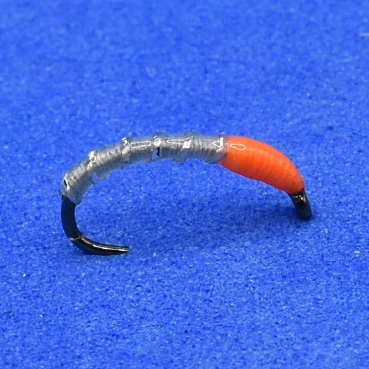 Soft plastic fishing lure with an orange head and ribbed gray body on a curved hook.