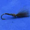 Dark fly fishing lure with a fluffy black tail and green ribbing on a curved hook, set on a blue background